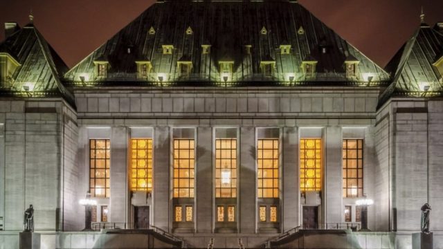 The Supreme Court of Canada building stands lit up at night.