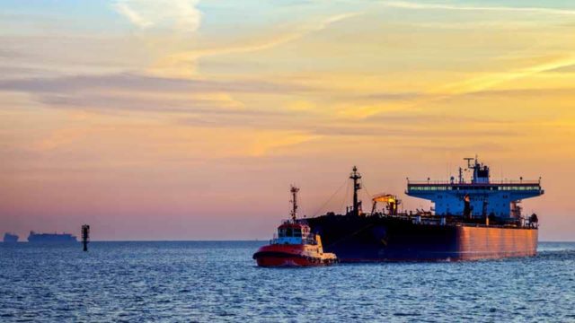 An oil tanker sits on the blue water at sunset.