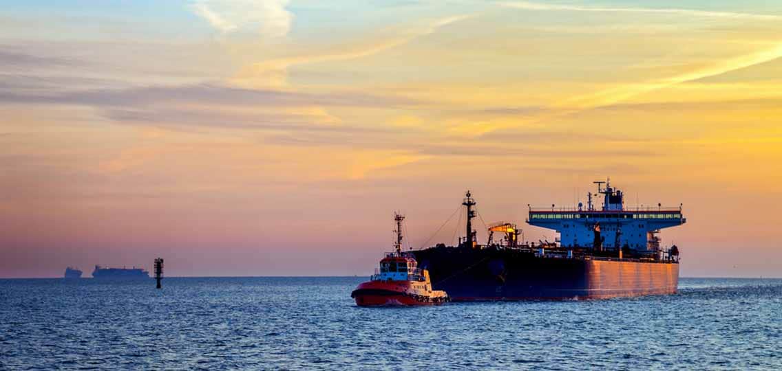 An oil tanker sits on the blue water at sunset.