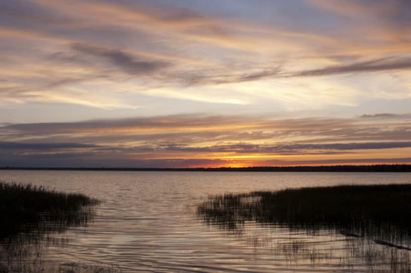 The mouth of a great lake opens into a large body of water at sunset.