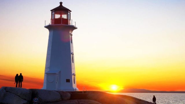 A lighthouse stands on a cliff at sunrise.