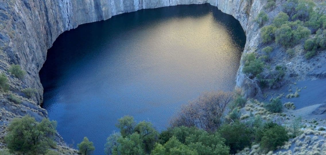 An aerial view of a large, round body of water surrounded by high cliffs.
