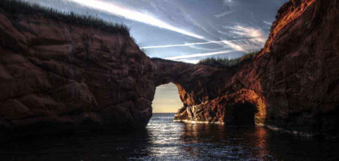Two rocky cliffs create a bridge over a large body of water.