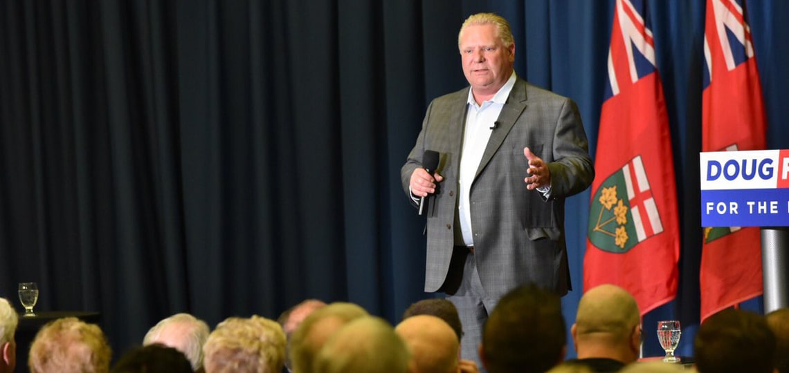 Doug Ford addresses an audience holding a microphone.