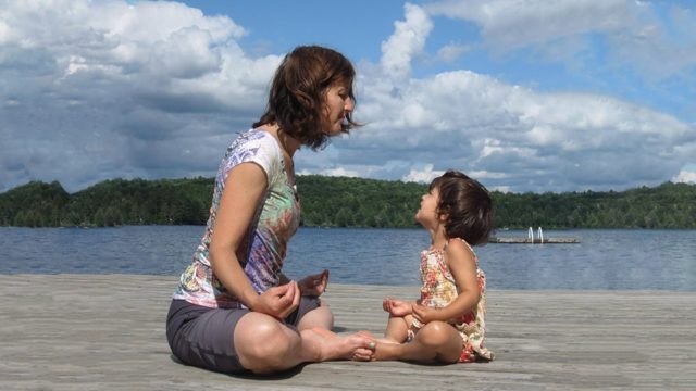 Cathy Orlando and her young daughter Sophia sit on a beach's shore and meditate.