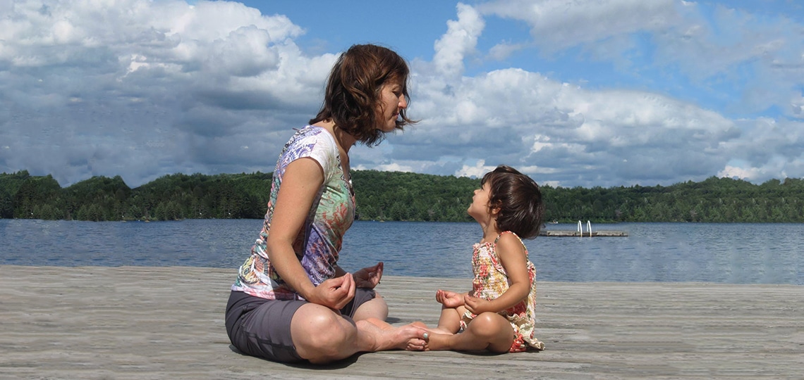 Cathy Orlando and her young daughter Sophia sit on a beach's shore and meditate.
