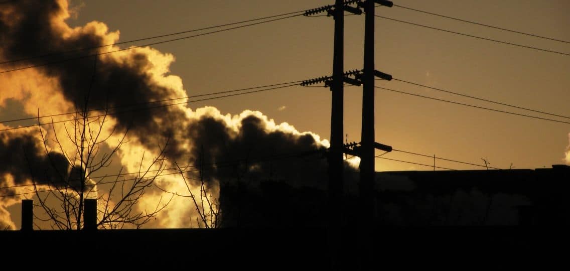 Smoke from a building billows into the sky as the sun sets.