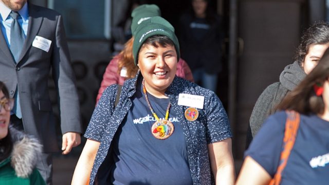 Ecojustice client Beze Gray walks in a group smiles and wears a green toque.