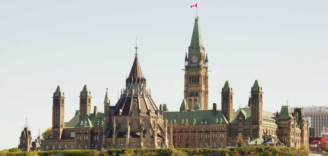 The rooftops of Canadian Parliament buildings include a view of the clock tower and a Canadian flag.