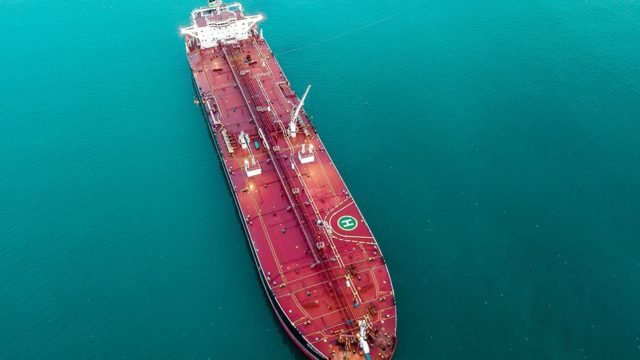 An aerial view looks down at a large oil tanker in the water.