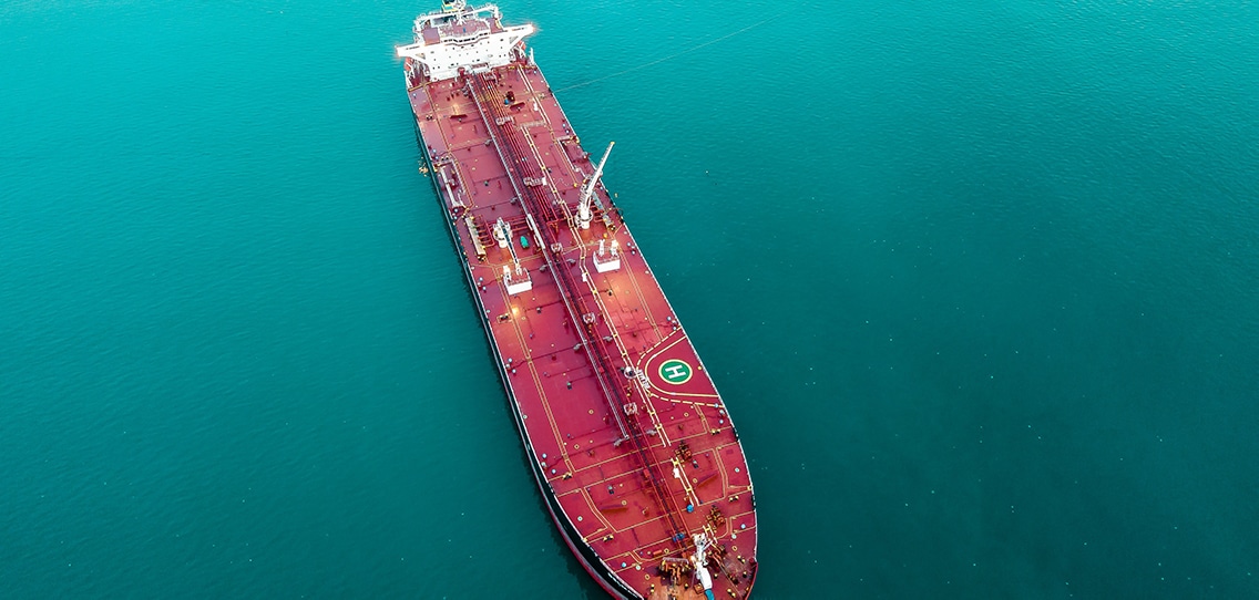 An aerial view looks down at a large oil tanker in the water.
