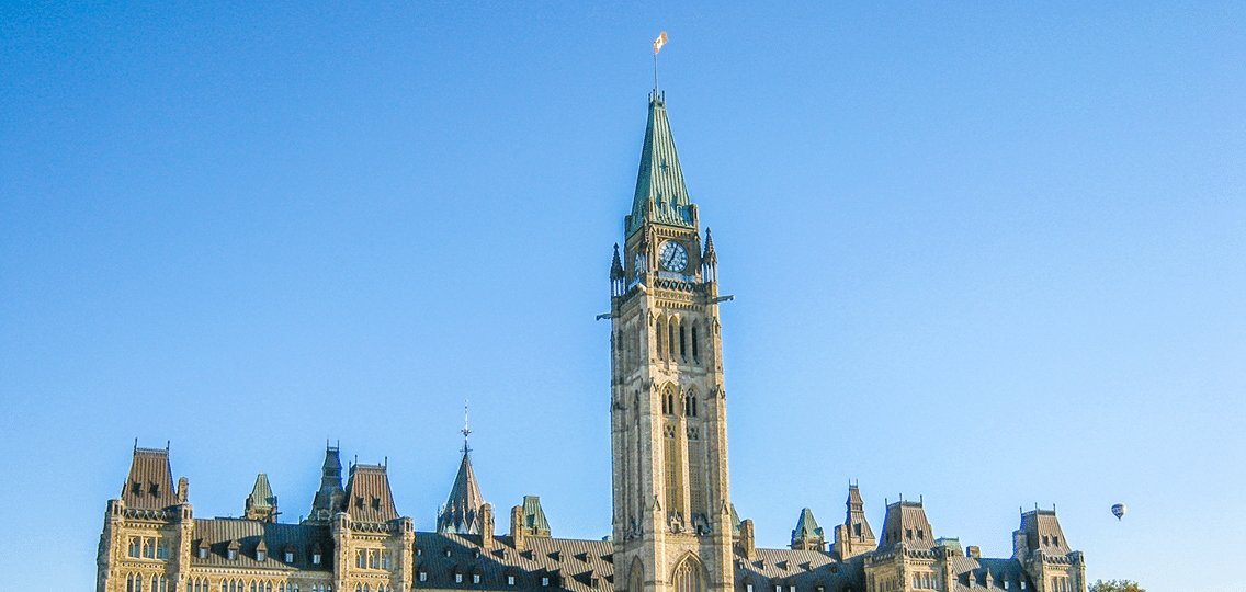 The rooftop of a Canadian Parliament building against the blue sky.