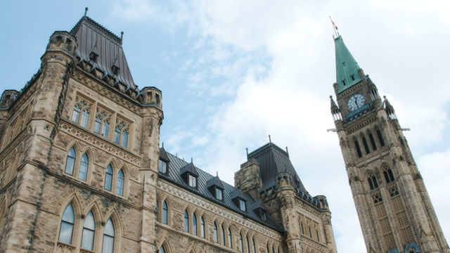 The clock tower and main building of the Canadian House of Commons from the ground.