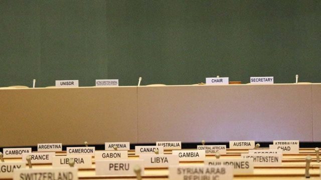 An empty United Nations conference room has country names placed on each seat.