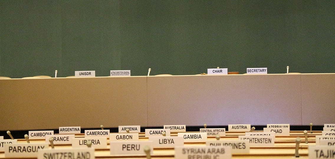 An empty United Nations conference room has country names placed on each seat.
