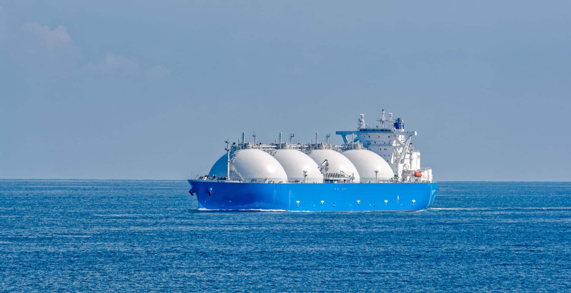 A tanker ship outfitted for transporting LNG is shown on the open sea.
