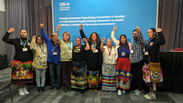 A group of frontline Indigenous delegates raise their fists in solidarity at the UN global plastics treaty negotiations.